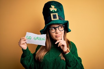 Young beautiful woman wearing green hat and glasses on saint patricks day celebration serious face...