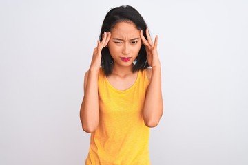 Obraz na płótnie Canvas Young chinese woman wearing yellow casual t-shirt standing over isolated white background with hand on head for pain in head because stress. Suffering migraine.