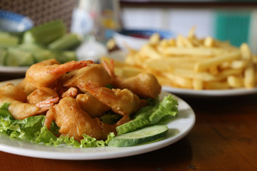 Fried shrimp and french fries basket isolated on potato background