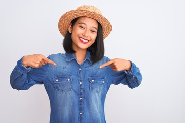 Young beautiful chinese woman wearing denim shirt and hat over isolated white background looking confident with smile on face, pointing oneself with fingers proud and happy.