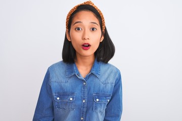 Young beautiful chinese woman wearing denim shirt standing over isolated white background afraid...
