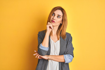 Redhead caucasian business woman over yellow isolated background covering ears with fingers with annoyed expression for the noise of loud music. Deaf concept.