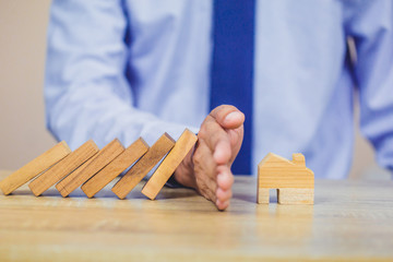 Property insurance. and security concept, businessman hand stopping risk the wooden blocks from...