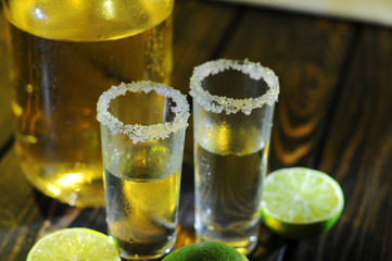 Alcoholic drink concept. Mexican tequila with lime and salt on rustic wood background. space for...