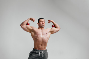 Sporty sexy guy posing on a white background with bright fruits. Diet. Healthy diet