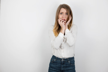 young beautiful blond woman standing on isolated white background looking scared, body language...