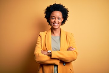 Young beautiful African American afro businesswoman with curly hair wearing yellow jacket happy...