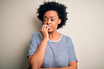 Fototapeta na wymiar Young beautiful African American afro woman with curly hair wearing striped t-shirt looking stressed and nervous with hands on mouth biting nails. Anxiety problem.