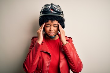 Young African American afro motorcyclist woman with curly hair wearing motorcycle helmet with hand on head for pain in head because stress. Suffering migraine.