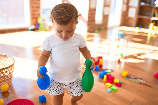 Adorable toddler playing around lots of toys at kindergarten