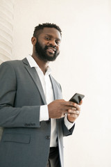 Below view of smiling Afro-American bearded businessman using messenger for online communication on phone