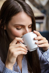 Beautiful young brunette woman drinking coffee