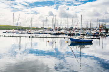 Yachts moored in a harbour on a partly cloudy summer day