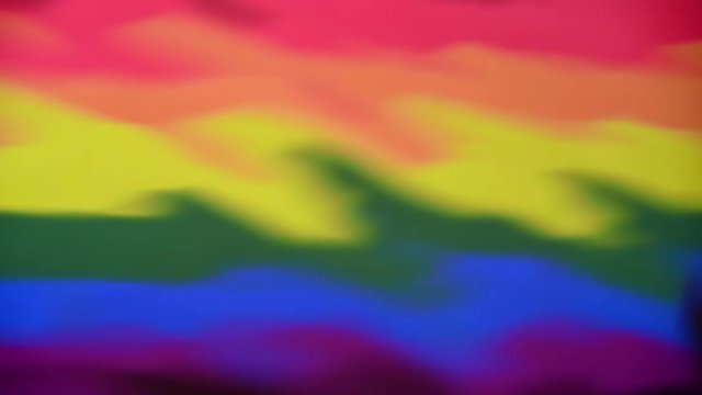 Gay Pride Flag reflection with multiple water drops along the lower edge and resulting ripples. Abstract background concept