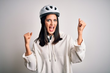 Young cyclist woman with blue eyes wearing bike helmet over isolated white background celebrating surprised and amazed for success with arms raised and open eyes. Winner concept.