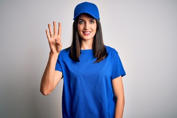 Young delivery woman with blue eyes wearing cap standing over blue background showing and pointing up with fingers number four while smiling confident and happy.