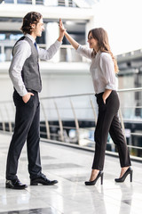 Fototapeta premium Beautiful business woman is giving high five and smiling to man during business meeting in office