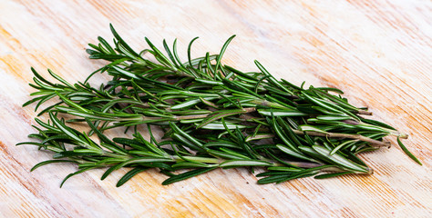 Green sprigs of rosemary on wooden surface