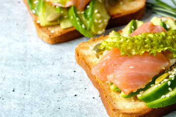 Toast with avocado and salmon fish on the table close-up.