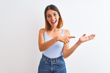 Beautiful redhead woman standing over isolated background amazed and smiling to the camera while presenting with hand and pointing with finger.