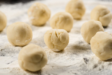 Fototapeta na wymiar close up view of raw dough balls for dumplings on flour