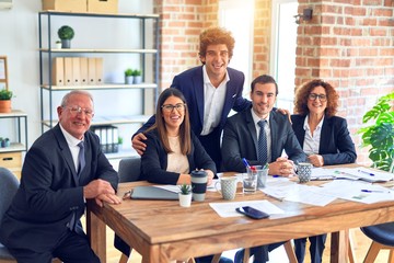 Obraz premium Group of business workers smiling happy and confident in a meeting. The boss standing and employees sitting with smile on face looking at the camera at the office