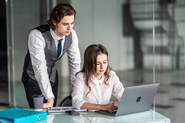 Two colleagues man and woman using laptop in office