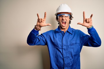 Young constructor man wearing uniform and security helmet over isolated white background shouting...