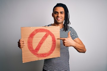 Young handsome african american man with dreadlocks holding banner with prohibited signal very...