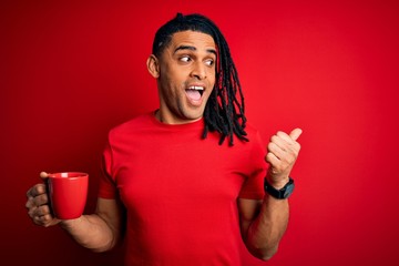 Young african american afro man drinking cup of coffe over red background pointing and showing with thumb up to the side with happy face smiling