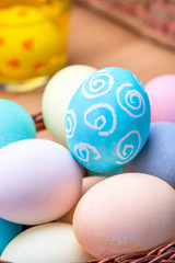 Easter eggs preparation - Young woman is drawing white egg with pastel wax crayon before dyeing colors at home kitchen table, close up, lifestyle