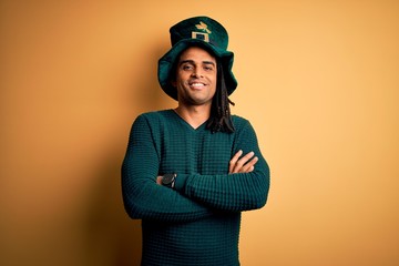 Young african american man wearing green hat with clover celebrating saint patricks day happy face smiling with crossed arms looking at the camera. Positive person.