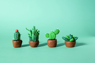 Handmade plasticine green cactuses and succulents in a pots.