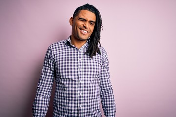 Young handsome african american afro man with dreadlocks wearing casual shirt winking looking at the camera with sexy expression, cheerful and happy face.