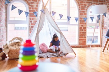 Beautiful toddler girl sitting on the floor playing with unicorn inside tipi at kindergarten © Krakenimages.com
