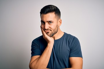 Fototapeta premium Young handsome man wearing casual t-shirt standing over isolated white background thinking looking tired and bored with depression problems with crossed arms.