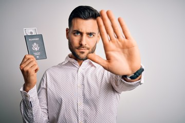 Young handsome tourist man holding united states passport id with dollars with open hand doing stop sign with serious and confident expression, defense gesture