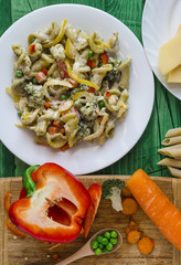pasta with vegetables and cheese on a white plate green background of home cooking vertical