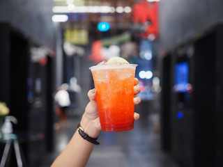 A plastic glass of iced strawberry rose sparkling soda and decorated with dried rose flower....