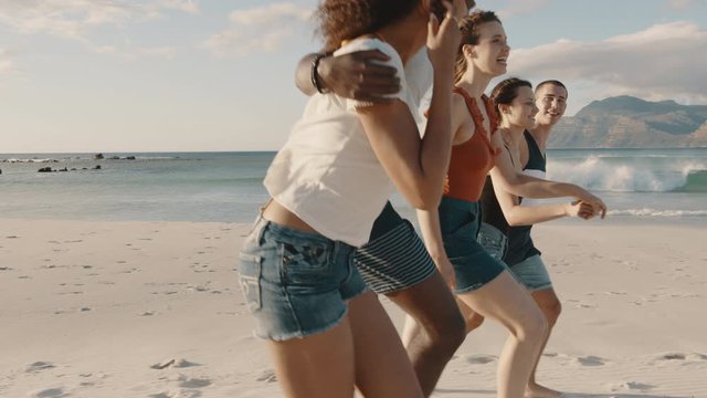 Group of friends walking along the beach. Young men and women enjoying on a summer beach vacation.