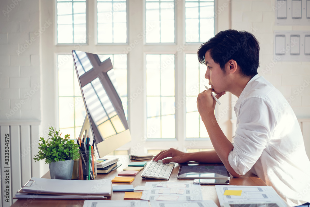 Wall mural designer man drawing a website outline and website ux app development on mobile phone.