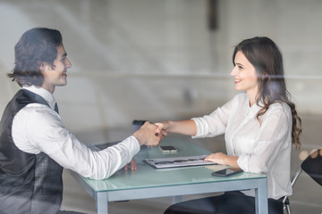 Friendly smiling businessman and businesswoman handshaking over the office desk after pleasant talk and effective negotiation, good relationships. Business concept photo