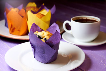 Cup of coffee and blueberry muffin on purple background