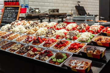 Belgian waffles with whipped cream, topping and fresh berries on showcase.