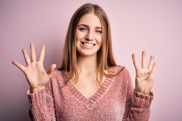Young beautiful redhead woman wearing casual sweater over isolated pink background showing and...