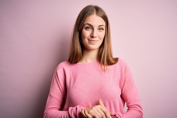 Fototapeta premium Young beautiful redhead woman wearing casual sweater over isolated pink background with hands together and crossed fingers smiling relaxed and cheerful. Success and optimistic