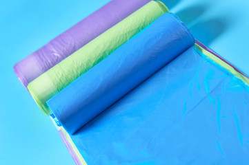 Row of rolls of disposable plastic garbage bag on blue background. Close-up