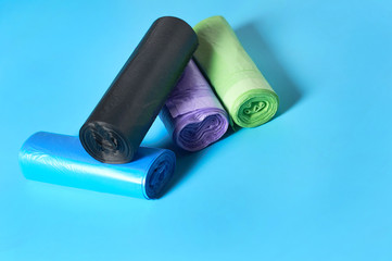 Heap of rolls of disposable plastic garbage bag on blue background. Copy space