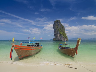 Fototapeta na wymiar view seaside of two long-tail boats floating in blue-green sea with cliff mountain and cloudy sky background, Ko Poda island, Krabi, southern of Thailand.