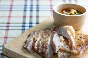 Slice grilled pork with fish sauce on wooden plate or table.